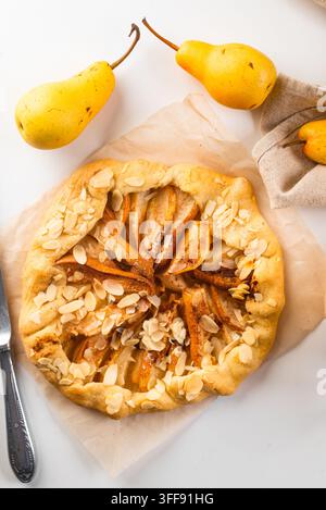 galette al forno o torta aperta con pera, cannella e fiocchi di mandorle sul tavolo Foto Stock