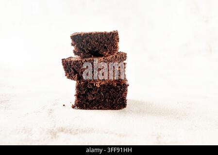 Molti pezzi di brownie al cioccolato fresco su un tavolo bianco. Deliziosa torta dolce al cioccolato fatta in casa Foto Stock