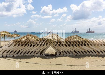 Una lunga fila di sdraio impilati e piegati sulla spiaggia di Limassol, Cipro Foto Stock
