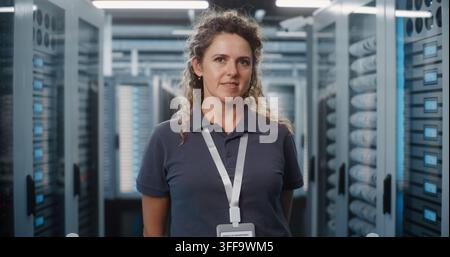 Specialista IT donna sicura di sé in piedi in una moderna sala server del data center. Donne nello STEM e nell'amministrazione di rete garantiscono un archiviazione cloud sicura e un funzionamento affidabile dell'infrastruttura server. Ritratto. Foto Stock