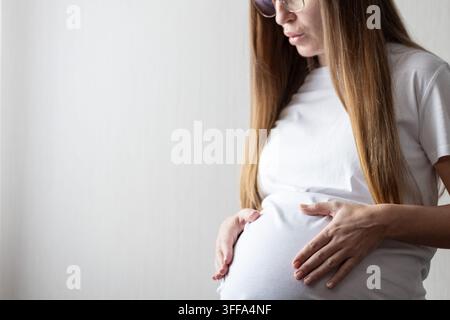 Donna incinta mette le mani sul ventre e fa esercizi di respirazione. Foto Stock