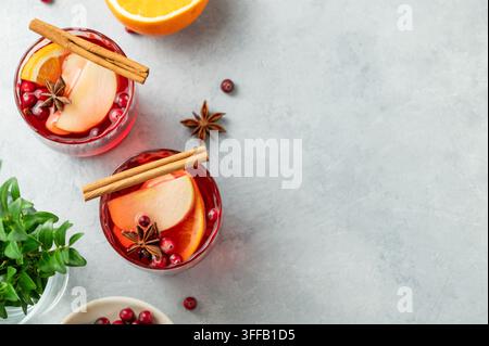 Una bevanda al mirtillo in due bicchieri su uno sfondo chiaro con cannella, bacche e ramo verde. Un punch tradizionale natalizio o vin brulè con o Foto Stock