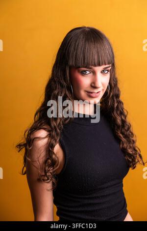Giovane donna con frangia e lunghi capelli ricci che sorride Foto Stock
