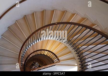 Vista dall'alto di una scala a chiocciola con gradini in legno e ringhiere in metallo all'interno di un edificio a Barcellona, Spagna Foto Stock
