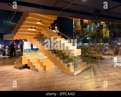 Vista interna del museo delle scarpe Bata a Toronto che mostra una moderna progettazione di scale in legno, vetrine e visitatori che esplorano le esposizioni. Foto Stock