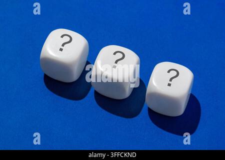 Tre dadi bianchi con punti interrogativi su uno sfondo blu. Processo decisionale, incertezza, valutazione del rischio, concetto di strategia. Foto Stock