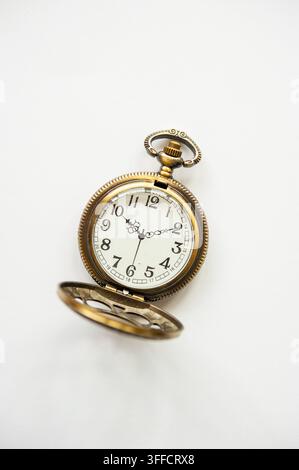 Orologio da tasca in ottone in stile antico isolato sul bianco, con cassa traforata ornata e quadrante decorativo con lancette e numeri neri Foto Stock