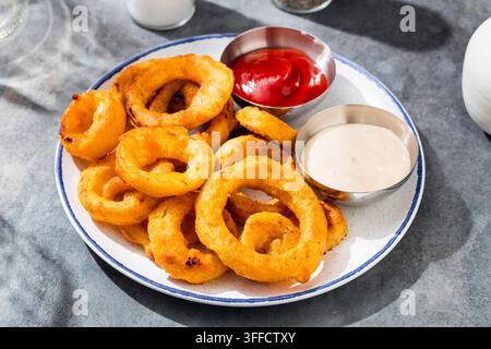 Anelli di cipolla impanati con birra fatta in casa con ketchup e salsa Foto Stock