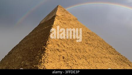 Antica piramide egiziana di Chefren che si erge sotto un raro doppio arcobaleno contro un drammatico cielo nuvoloso a Giza, un'immagine di punto di riferimento mozzafiato, ideale per Foto Stock