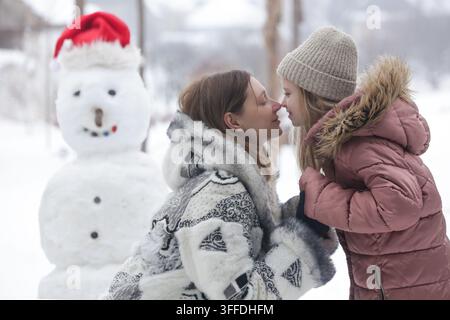 Madre e figlia trascorrono del tempo insieme all'aperto nel paesaggio invernale innevato Foto Stock
