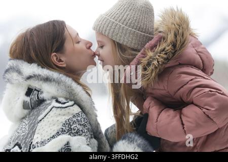 Madre e figlia trascorrono del tempo insieme all'aperto nel paesaggio invernale innevato Foto Stock