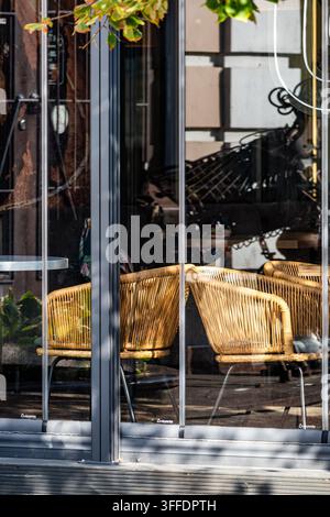 Interno di un caffè in stile europeo moderno visibile attraverso le pareti di vetro con sedie tessute eleganti Foto Stock