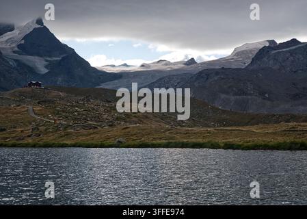 Lago Stellisee con il rifugio FLuhalp e vette con enormi ghiacciai sopra nelle Alpi del Vallese vicino a Zermatt in Svizzera Foto Stock