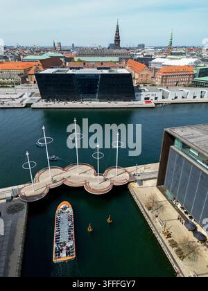 Vista aerea del ponte Cirkelbroen con le sue piattaforme circolari sopra il canale, che mostra una barca sul canale che passa e l'edificio Black Diamond a Copenaghen Foto Stock