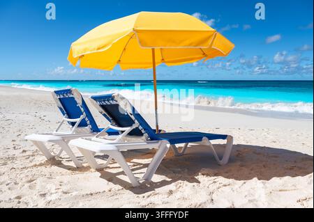 Due sedie a sdraio e ombrello giallo sulla spiaggia di Shoal Bay, Anguilla. Foto Stock