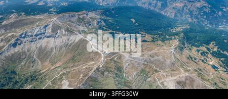 Paesaggio panoramico aereo di grandi dimensioni con il picco Fraiteve e l'area sciistica di Sestriere dall'est, scattato da un aliante nella luce estiva brillante, Italia Foto Stock