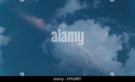 Nuvole bianche e sottili fluttuano contro un cielo blu profondo durante il crepuscolo, catturando un'atmosfera pacifica di serenità, bellezza naturale e quieta contemplazione Foto Stock
