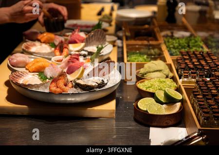 Vassoio di frutti di mare freschi con una varietà di pesci, guarnito con erbe e agrumi, disposto meravigliosamente su un tavolo di legno per un piacere culinario. Foto Stock