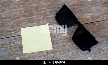 Post-it vuoto e occhiali da sole su superficie di legno Foto Stock