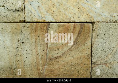 Prima vista di blocchi di muro in pietra naturale con texture ruvida e porosa e tonalità beige-grigio. Mostra venature dettagliate, increspature naturali e stratificazione orizzontale. Foto Stock