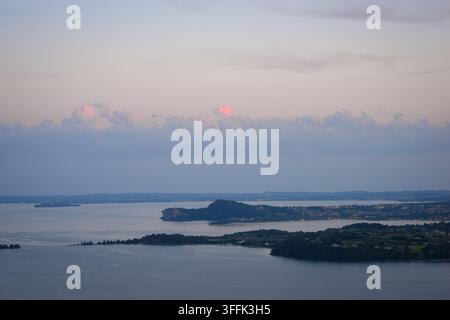 L'ultima luce del sole illumina le cime delle nuvole sopra il lago di Garda, Italia. Foto Stock
