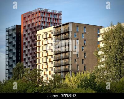 Foto ad angolo basso di moderni grattacieli per uffici e residenziali che si ergono sopra gli alberi verdi a Vilnius, Lituania. Foto Stock