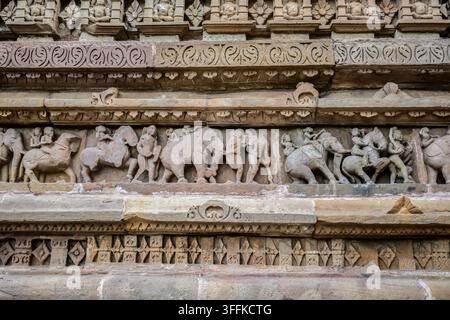 Un fregio in pietra dettagliato che raffigura una processione di elefanti con numerose figure scolpite, Khajuraho, India Foto Stock