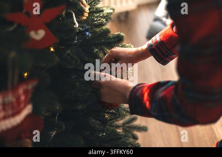 Bambino decora l'albero di Natale con una pallina a casa Foto Stock