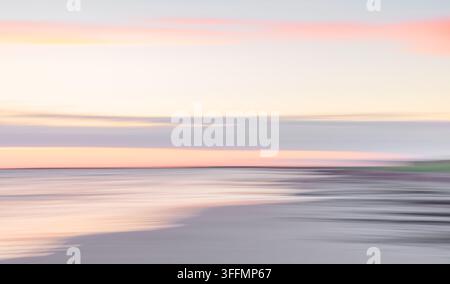 Un paesaggio marino astratto sfocato che mostra morbide sfumature pastello sotto un cielo di tramonto luminoso con onde d'acqua lisce che si fondono con l'orizzonte nebbioso Foto Stock