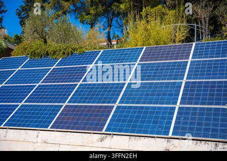 Pannelli solari installati su un tetto, che mostrano celle fotovoltaiche blu sotto la luce intensa del sole con vegetazione sullo sfondo, Croazia Foto Stock