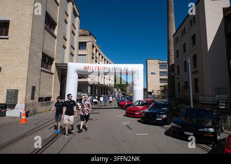 Kemptthal, Zurigo, Svizzera, 6 settembre 2026. Visitatori che camminano sotto un arco gonfiabile Motorworld oltrepassando auto sportive alla vigilia di un incontro di auto giapponesi Foto Stock