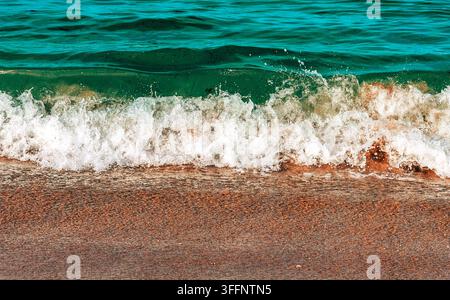 Piccole onde che si infrangono su una spiaggia sabbiosa Foto Stock