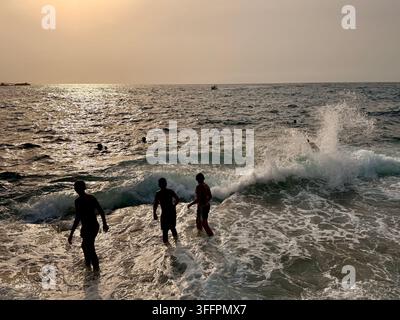 Persone che nuotano nel Mar Mediterraneo al tramonto a El Haouaria, sulla penisola di Cap Bon in Tunisia, una meta costiera popolare nel nord della Tunisia Foto Stock