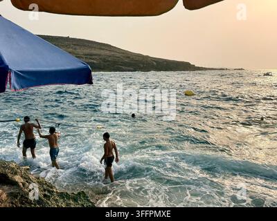 Persone che nuotano nel Mar Mediterraneo al tramonto a El Haouaria, sulla penisola di Cap Bon in Tunisia, una meta costiera popolare nel nord della Tunisia Foto Stock