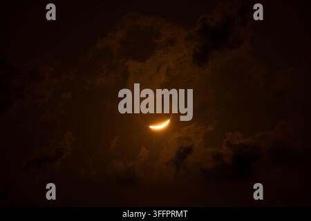 Prima pianata drammatica di un'eclissi solare con una corona dorata luminosa che emerge dietro la silhouette scura della luna. Scena cosmica astratta con velo fumoso Foto Stock