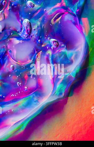 Vista macro astratta di bolle liquide traslucide e pigmento iridescente fluente, che mescola un vivace blu neon, viola, rosa, verde e arancione in un globo Foto Stock