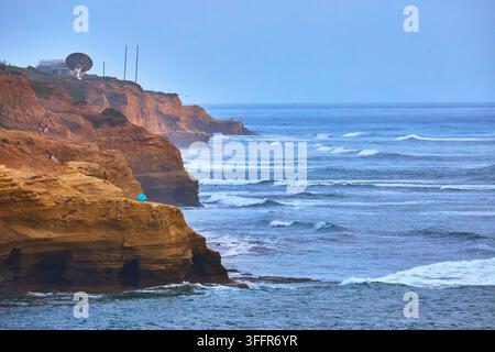 Le onde si avvicinano alle scogliere di arenaria delle Sunset Cliffs a San Diego, in California, mentre l'oceano si estende in lontananza. La costa rocciosa e la calma Foto Stock