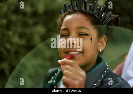 Ritratto di un bambino nero in costume di Halloween che mangia caramelle all'aperto Foto Stock