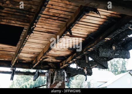 Travi di legno bruciate e struttura del tetto carbonizzata dopo un incendio. Danni da incendio, edificio distrutto, legno bruciato. Assicurazione sulla proprietà contro gli incidenti Foto Stock