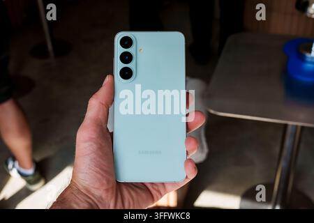 RIGA, LETTONIA. 25 agosto 2026. Mano maschile che tiene la versione verde chiaro dello smartphone Samsung Galaxy S26 FE mostrando la copertura posteriore e il triple Foto Stock