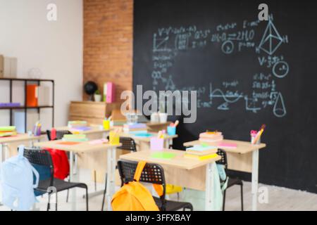 Educazione e apprendimento accademico, aula vuota con banchi e lavagna con complesse formule matematiche ed equazioni scientifiche per la scuola Foto Stock
