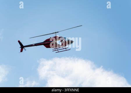 Bakewell, Inghilterra, Regno Unito - 05 settembre 2026: Vista di un elicottero rosso che vola in un cielo blu terso. Foto Stock