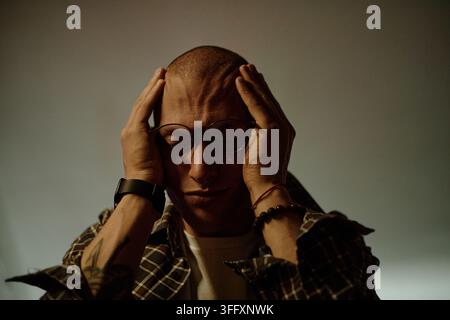 Uomo stressato che tiene la testa e soffre di emicrania e ansia Foto Stock