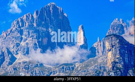 Maestosa paesaggio alpino di pinnacoli montuosi affilati e nuvole basse sotto un cielo blu in Italia, Dolomiti italiane in autunno Foto Stock