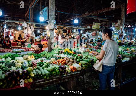 Affollato mercato di prodotti freschi con bancarelle di ortaggi e acquirenti locali a Siem Reap, in Cambogia. Foto Stock