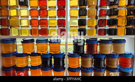 Barattoli di miele naturale biologico puro in varie tonalità ambrate dorate in mostra in un mercato di un villaggio georgiano Foto Stock