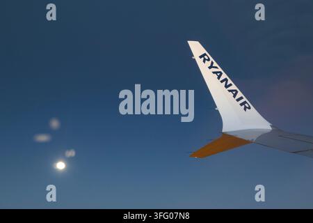 guardando fuori dal finestrino di un volo Ryanair con la luna piena in un cielo serale limpido Foto Stock
