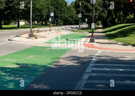 Pedone che attraversa una strada su un passaggio pedonale dipinto di verde accanto a una pista ciclabile, simboleggiando una mobilità urbana sostenibile e un'infrastruttura cittadina più sicura Foto Stock
