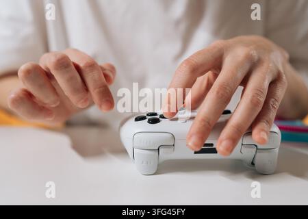 Gamer femminile che tiene un controller di videogame wireless bianco contemporaneo, gioca attivamente e si impegna nel divertimento elettronico su sfondo bianco. Foto Stock
