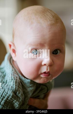 Ritratto di un bambino curioso che guarda la telecamera con la madre a casa Foto Stock